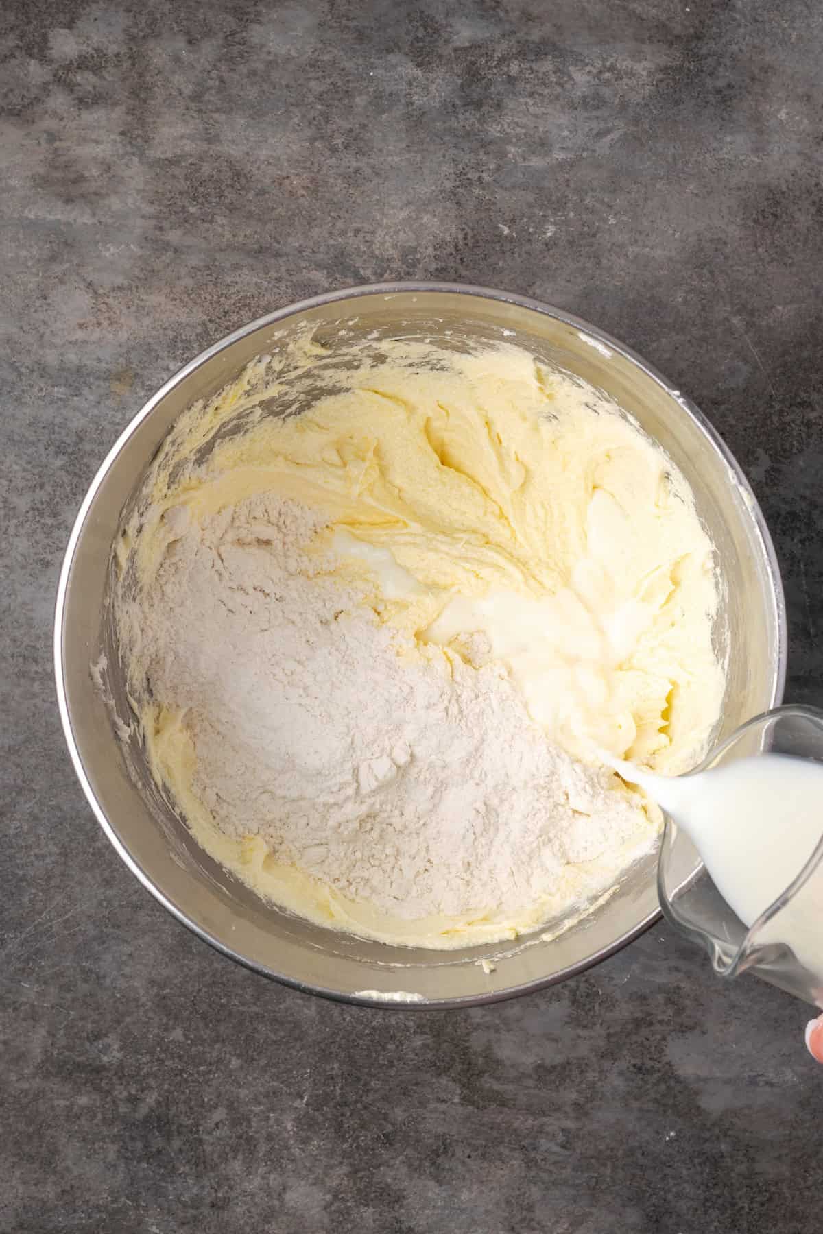 Milk being added to wet cupcake batter along with a portion of the dry ingredients.
