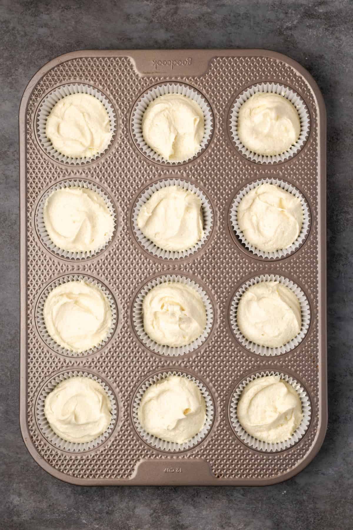 Overhead view of a lined cupcake pan filled with batter.