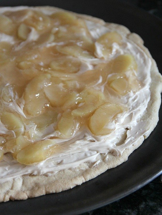 Apple pie filling spread over giant sugar cookie with cream cheese frosting