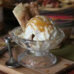 A scoop of Caramel Apple Ice cream in a clear glass dessert dish