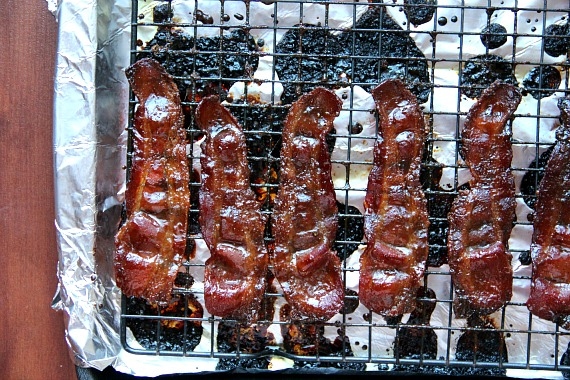 Candied bacon on a cooling rack inside a foil-lined baking pan