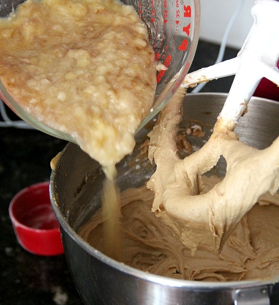 Mashed bananas being added to cupcake batter in a stand mixer bowl