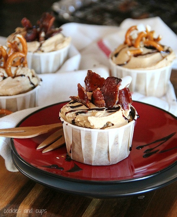Frosted banana chocolate chip cupcake with candied bacon garnish on a plate