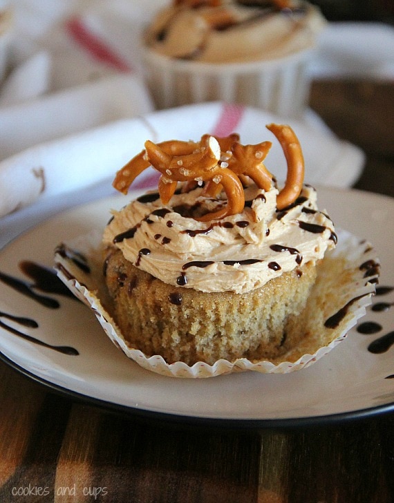 Frosted banana cupcake with chocolate drizzle and pretzel pieces on top