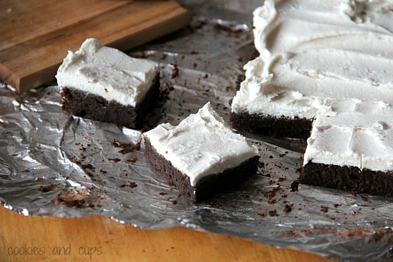 Pumpkin brownies with white pumpkin spice frosting on foil.
