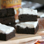 Side view of stacked pumpkin brownies with white pumpkin spice frosting