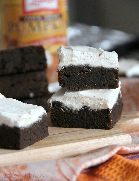 Side view of stacked pumpkin brownies with white pumpkin spice frosting