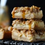 three apple cheesecake bars with caramel dripping, stacked