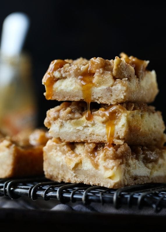 three apple cheesecake bars with caramel dripping, stacked