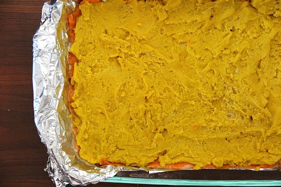 Top view of yellow dough over orange dough in a foil-lined baking pan