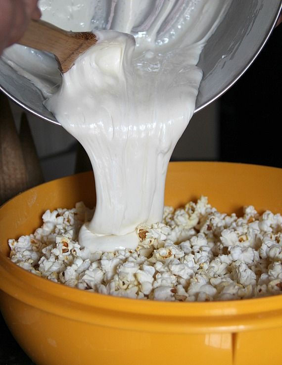 Melted marshmallow being poured over popcorn in a bowl