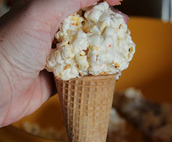 A popcorn ball being pressed on top of a sugar cone