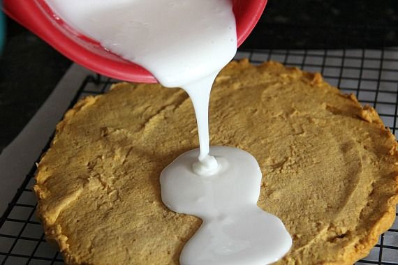 Glaze being poured over baked pumpkin shortbread on a cooling rack