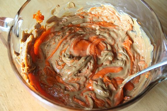 Peanut butter and melted candy corn being mixed together in a bowl