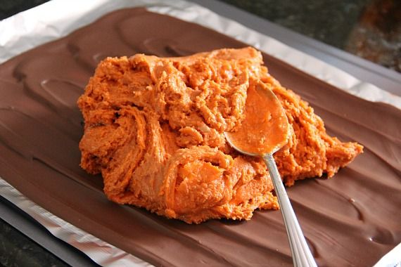 Homemade butterfinger filling being spread over chocolate layer on a sheet pan