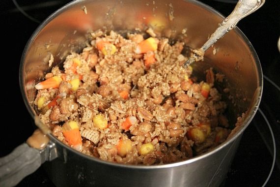 Chex cereal and candy corn with peanut butter in a saucepan