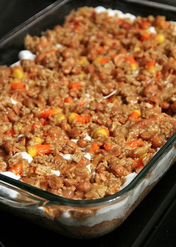 Layered scarecrow bars with crust, marshmallows and candy corn cereal mixture in a 9x13 pan