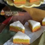 Three wedges of Candy Corn Sugar Cookie bars on parchment paper