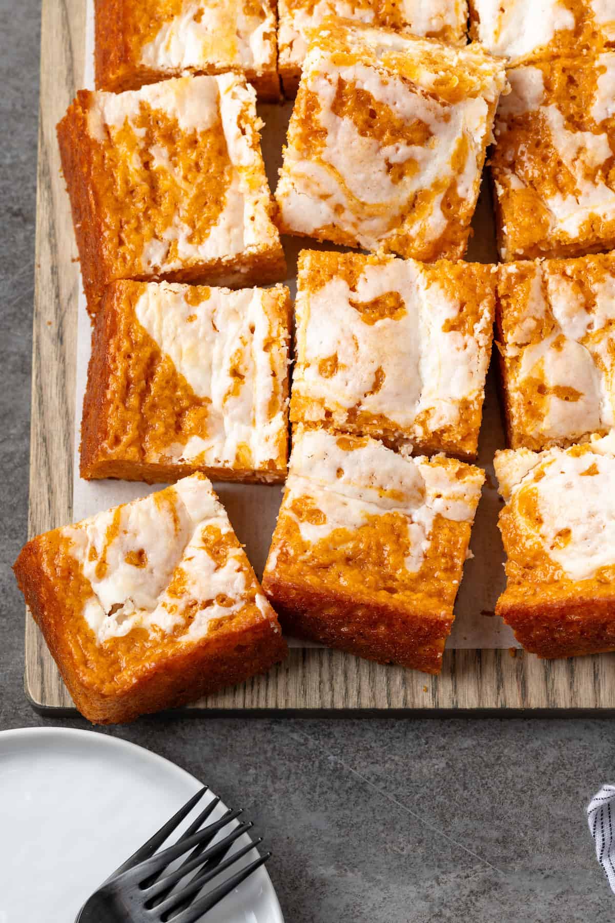 Overhead view of pumpkin cream cheese bars on a wooden board.