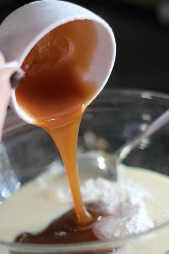 Caramel sauce being added to a mixing bowl with flour and sweetened condensed milk