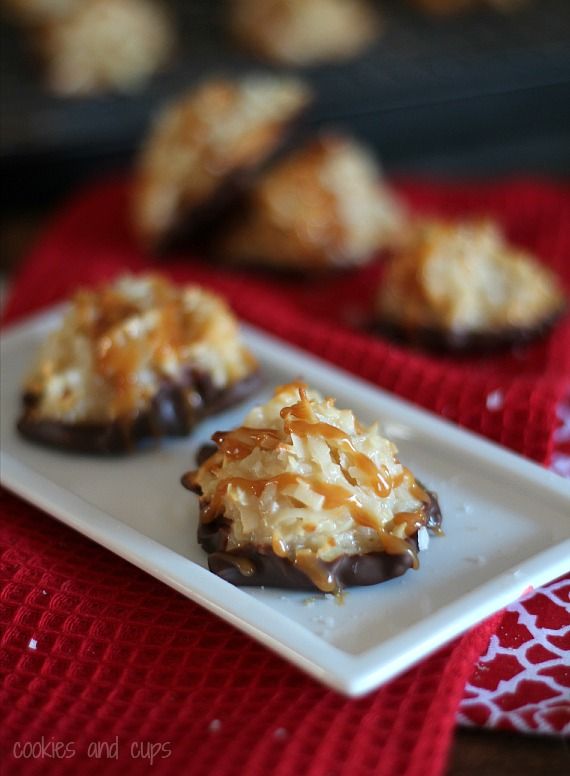 Two chocolate dipped coconut macaroons with caramel drizzle on a plate