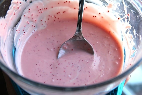 Pink melted candy cane kisses in a mixing bowl with a spoon