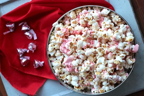 Top view of a bowl of popcorn with melted pink candy cane kiss candy drizzle