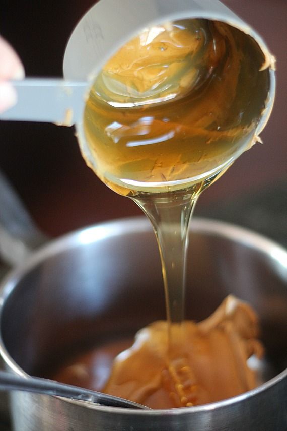 A measuring cup of honey being added to a mixing bowl