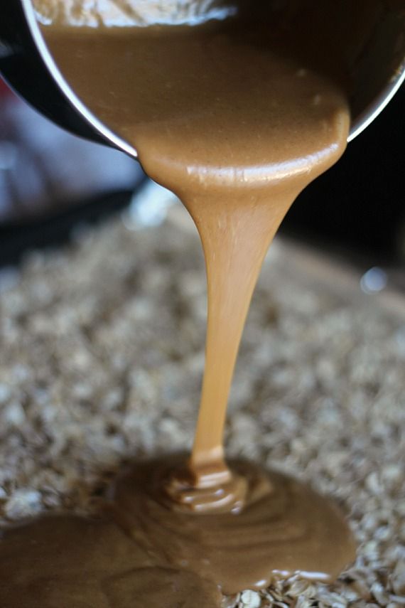 Melted peanut butter mixture being poured over oats