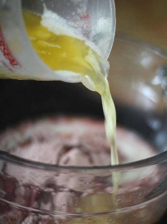 Melted butter being poured into dry cake mix in a bowl