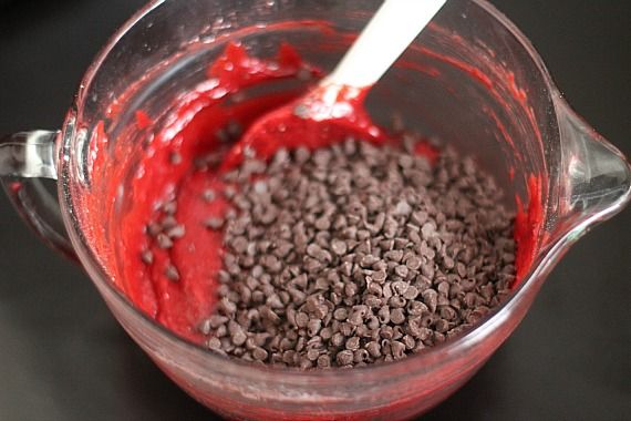 Mini chocolate chips added to a bowl of red cake batter