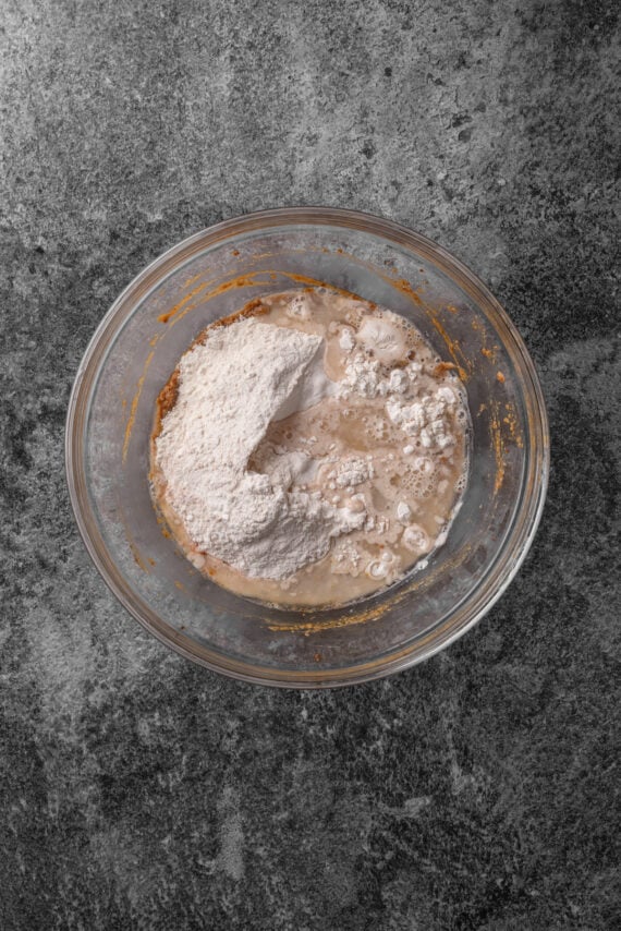 Dry ingredients added to wet ingredients in a glass bowl.