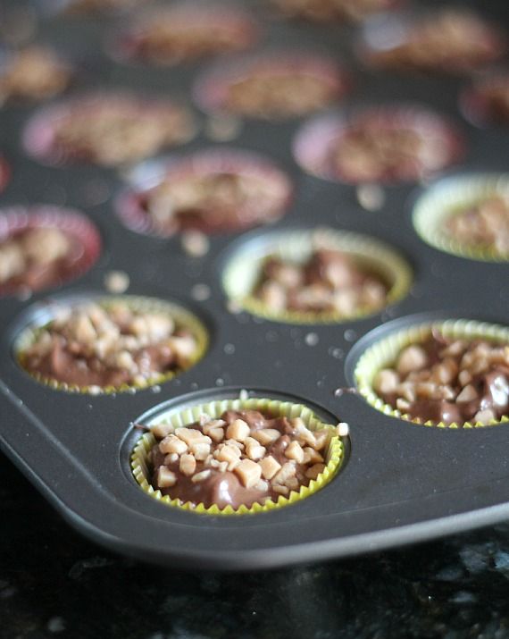 Crockpot candy inside lined muffin wells, sprinkled with crushed nuts.
