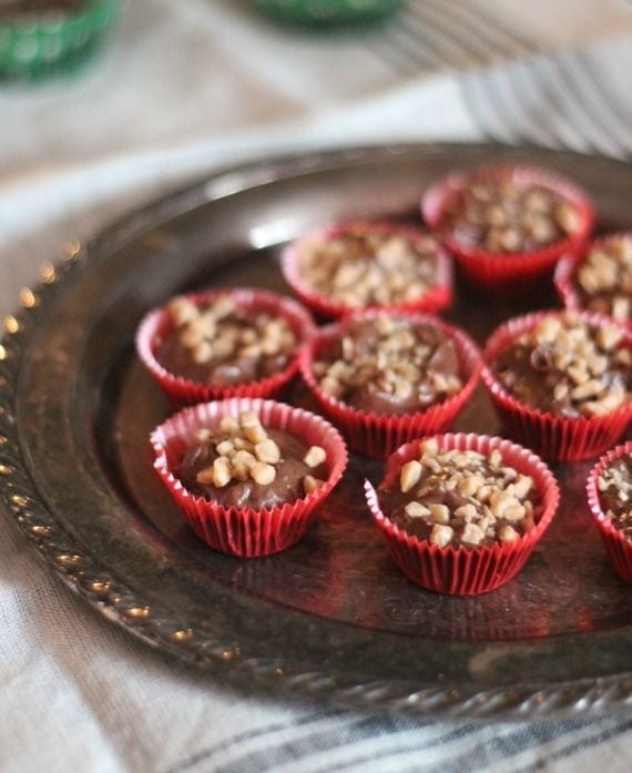 Assorted crockpot candy inside red cupcake liners on a plate.