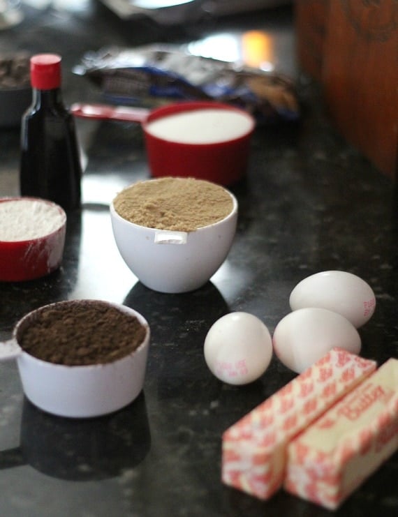 Baking ingredients on a countertop, including butter, eggs, cocoa powder, brown sugar, flour
