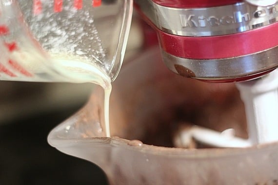Melted butter being poured into chocolate batter in a stand mixer