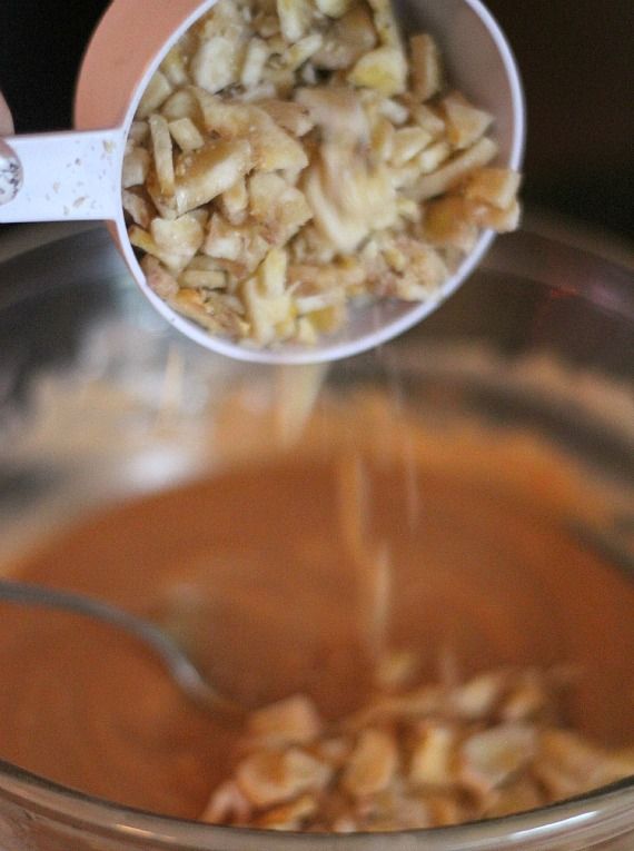 Banana chips being added to peanut butter fudge ingredients in a double boiler