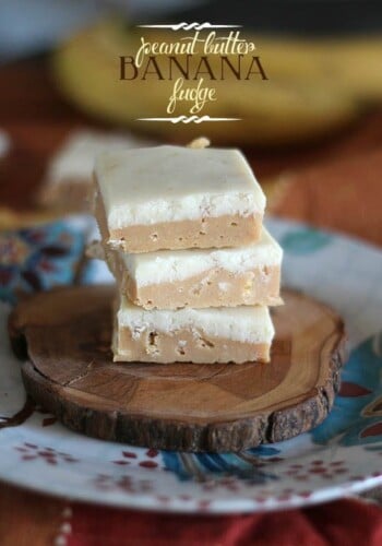 Three squares of Peanut Butter Fudge stacked on a wooden slice