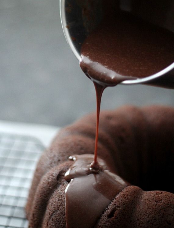 Chocolate glaze being poured over chocolate bundt cake