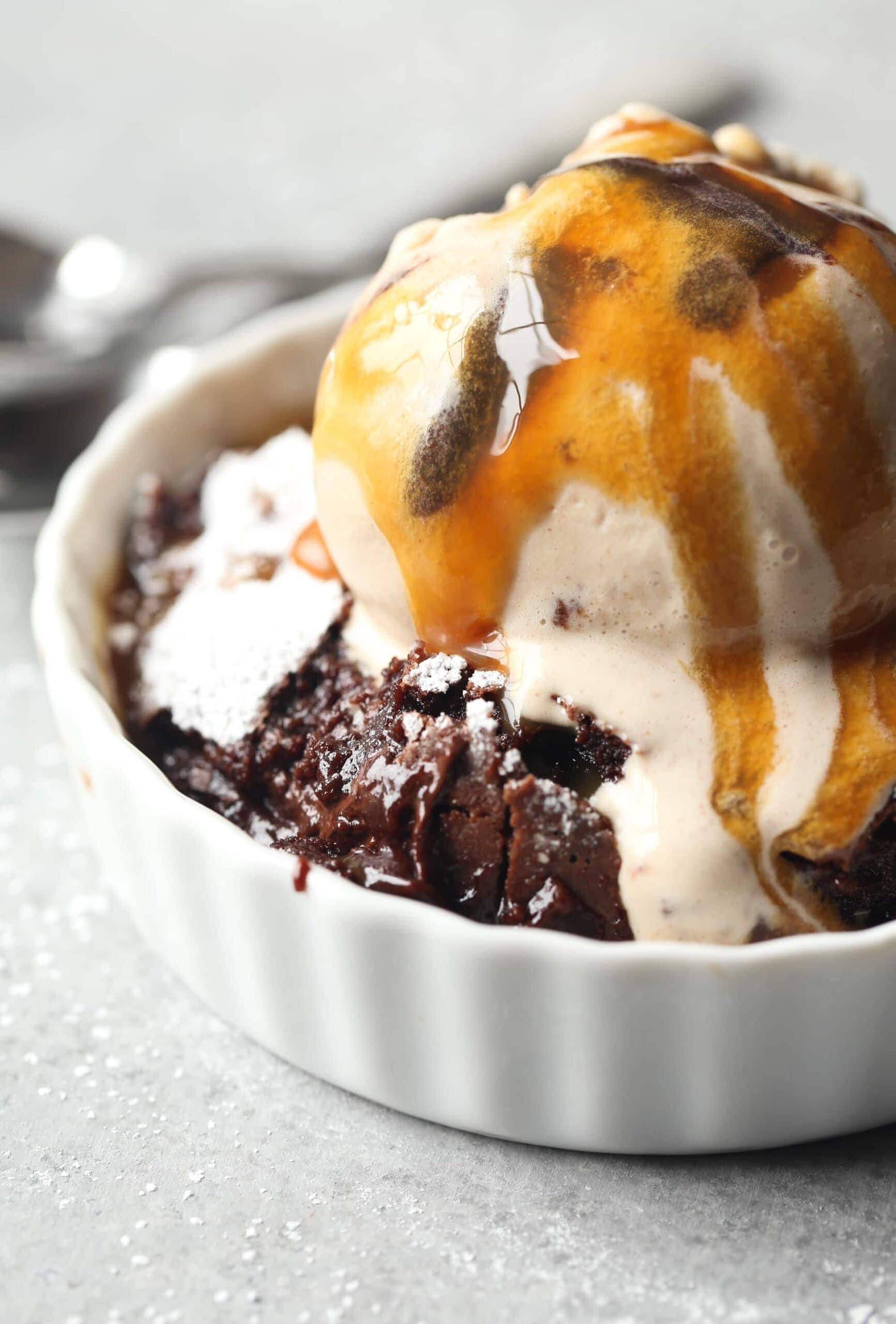 Close-up of Brownie Pudding with vanilla ice cream and caramel sauce in a ramekin