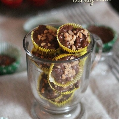 A glass mug filled with assorted crockpot candy wrapped in cupcake liners.