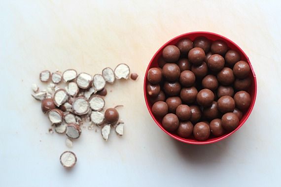 Chopped malted milk balls next to a bowl of malted milk balls