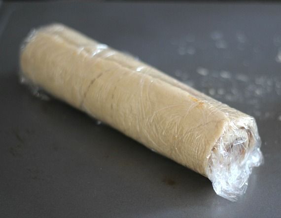 A log of rolled-up crescent roll dough spread with Biscoff spread and wrapped in plastic