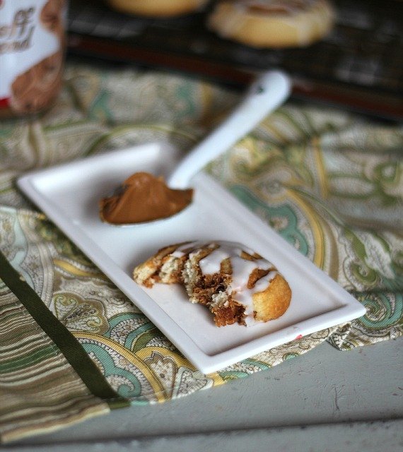 A piece of Biscoff Crescent roll pinwheel cookie on a plate with a spoonful of Biscoff spread