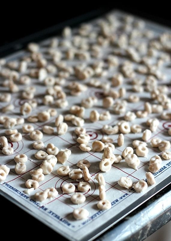 White chocolate coated cheerios spread out on a baking sheet