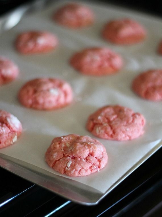 Rows of baked strawberry cake mix cookies on a parchment lined baking sheet.