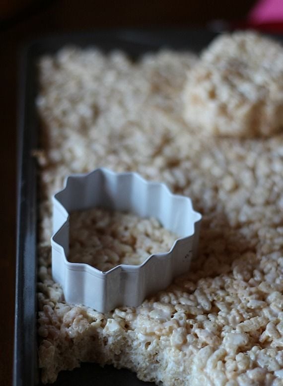 Heart-shaped cookie cutter in a pan of rice krispie treats