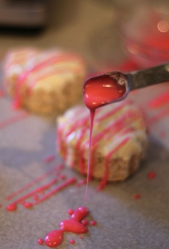 Red drizzle being added to heart-shaped rice krispie treats