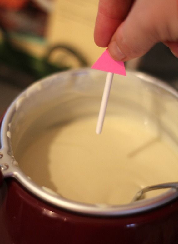 Lollipop stick being dipped in melted white chocolate