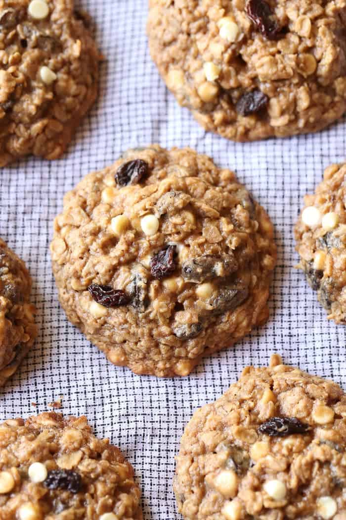 Close up of rows of oatmeal raisin cookies on a white cloth.